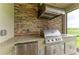Close-up of outdoor grill, including stainless steel grill, cabinets, and stone backsplash at 5810 Brandon Run, Bradenton, FL 34211