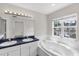 Bright bathroom featuring a double vanity, soaking tub, and natural light from a large window at 6418 Rosefinch Ct # 103, Lakewood Ranch, FL 34202