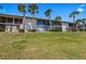 Exterior view of waterfront condo building with lush green lawn and palm trees at 6500 Flotilla Dr # 126, Holmes Beach, FL 34217