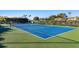 Bright blue tennis court surrounded by green foliage offering a vibrant recreational space for residents at 6500 Flotilla Dr # 126, Holmes Beach, FL 34217