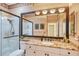 Bathroom with granite countertops, white cabinets, large mirror, and glass-enclosed shower at 6642 Oakland Hills Dr, Lakewood Ranch, FL 34202