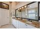 Bright bathroom with dual sinks, granite countertop, and a large mirror, offering a luxurious feel at 6642 Oakland Hills Dr, Lakewood Ranch, FL 34202