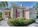 Charming home exterior with stone accents, red shutters, landscaped garden and well-manicured lawn at 6642 Oakland Hills Dr, Lakewood Ranch, FL 34202