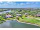A serene aerial view of lakeside houses adjacent to a lush green golf course, with well-manicured lawns and mature trees at 7408 S Serenoa Dr, Sarasota, FL 34241