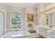 Bright bathroom with a garden view from the soaking tub, tiled floors, and white cabinets at 7408 S Serenoa Dr, Sarasota, FL 34241