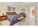 Neutral bedroom featuring a patterned bedspread, bench, and neutral tile flooring at 7408 S Serenoa Dr, Sarasota, FL 34241