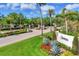 Elegant community entrance with manicured landscaping, a decorative sign, and palm trees lining the entrance road at 7408 S Serenoa Dr, Sarasota, FL 34241