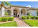 Charming home with arched entry, landscaped walkway, and manicured lawn at 7408 S Serenoa Dr, Sarasota, FL 34241