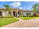 Inviting single-story home with manicured landscaping, brick driveway, and charming front entry at 7408 S Serenoa Dr, Sarasota, FL 34241