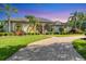 Single-story home featuring a well-manicured lawn, lush landscaping, and a circular brick driveway at 7408 S Serenoa Dr, Sarasota, FL 34241