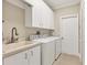 Bright laundry room featuring a sink, washer, dryer, and white cabinets at 7408 S Serenoa Dr, Sarasota, FL 34241