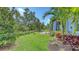 Beautifully landscaped backyard with green grass, tropical plants, and a serene patio area at 8110 Trimbelle Ter, Parrish, FL 34219