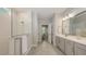 Bright bathroom featuring a glass shower with white subway tiles and a double vanity with gray cabinets at 8110 Trimbelle Ter, Parrish, FL 34219