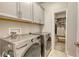 Laundry room with gray cabinets, modern washer and dryer, and access to a spacious walk-in closet at 8110 Trimbelle Ter, Parrish, FL 34219