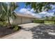 Beige home featuring a 3-car garage, landscaped yard, and long driveway at 8223 Snowy Egret Pl, Bradenton, FL 34202