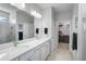 Bright bathroom features double sinks with white cabinets and marble countertops, and a glass door shower at 8313 Ocean Tides Cv, Parrish, FL 34219