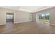 Spacious living room with wood-look floors, tray ceiling, and sliding glass doors leading to outdoor space at 10027 Cross River Trl, Parrish, FL 34219