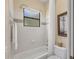 Bright bathroom featuring a tub with tile surround and decorative accents, plus a window for natural light at 11551 30Th E Cv, Parrish, FL 34219