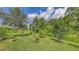 A spacious green backyard features mature trees, shrubbery and a bird house, providing a serene outdoor space at 13130 50Th E Ct, Parrish, FL 34219