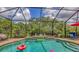 A beautiful screened pool with blue tiles and a stone waterfall feature sits adjacent to outdoor seating at 13130 50Th E Ct, Parrish, FL 34219