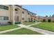Exterior view of the condo building featuring yellow walls, a red tile roof, and a well-manicured lawn at 1431 57Th W St # 1431, Bradenton, FL 34209