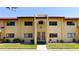 Exterior view of the condo featuring yellow walls, a red tile roof, and a well-manicured lawn at 1431 57Th W St # 1431, Bradenton, FL 34209