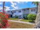 Charming two-story townhome with white exterior, green lawn, and blossoming red plants at 1535 Pleasant Rd # H5, Bradenton, FL 34207