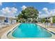 Large community pool surrounded by sun loungers, umbrellas, and lush greenery under a bright sky at 1535 Pleasant Rd # H5, Bradenton, FL 34207