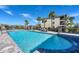 Inviting community pool surrounded by lounge chairs, palm trees, and a black metal safety fence at 17704 Gawthrop Dr # 102, Bradenton, FL 34211