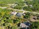 Aerial view of three homes with screened in pools, surrounded by lush vegetation and bordering a busy street at 18033 Edgewater Dr, Port Charlotte, FL 33948