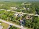 Wide aerial view of the neighborhood with three homes featuring screened-in pools and bordered by lush vegetation and roads at 18033 Edgewater Dr, Port Charlotte, FL 33948