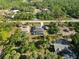 Aerial view of three homes with screened in pools, surrounded by lush vegetation and bordering a busy street at 18033 Edgewater Dr, Port Charlotte, FL 33948