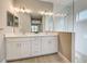 Bright bathroom featuring double vanity, a large mirror, and a walk-in shower with glass enclosure at 208 Potenza Loop, Nokomis, FL 34275
