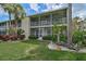 Inviting condo with screened balconies, lush lawn, and tropical landscaping showcasing attractive curb appeal at 208 Silver Lake Dr # 101, Venice, FL 34292