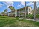 Condo featuring screened balconies, well-maintained lawn, and tropical landscaping offering attractive curb appeal at 208 Silver Lake Dr # 101, Venice, FL 34292