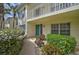 Inviting condo exterior featuring a walkway, manicured shrubbery, and a private balcony with white railings at 208 Silver Lake Dr # 101, Venice, FL 34292
