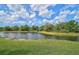 Scenic view of a serene pond surrounded by lush greenery and mature trees under a partly cloudy sky at 208 Silver Lake Dr # 101, Venice, FL 34292