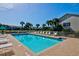 Community pool offering lounge chairs, umbrellas, and palm trees with condos in the background at 208 Silver Lake Dr # 101, Venice, FL 34292