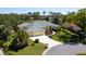 Aerial view of a home with lush landscaping, gray tile roof, and three car garage at 2196 Muskogee Trl, Nokomis, FL 34275