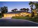 Exterior elevation view of house featuring a three car garage, tile roof and landscaped lawn at dusk at 2196 Muskogee Trl, Nokomis, FL 34275