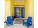 Welcoming front porch with blue Adirondack chairs and a view of the home's interior through double doors at 2196 Muskogee Trl, Nokomis, FL 34275