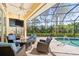 Covered patio with comfortable seating overlooks a refreshing pool and lush landscaping at 2196 Muskogee Trl, Nokomis, FL 34275