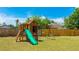 Backyard play set with slide, swing, and climbing wall, set against a wood fence at 2237 Lockwood Meadows Cir, Sarasota, FL 34234