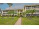 Multi-story condo building with manicured lawn and mature palm trees in a tropical setting at 225 Hourglass Way # 306, Sarasota, FL 34242