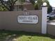 Entrance to Trinity Village Condominium complex with prominent signage and manicured landscaping at 2938 Clark Rd # 203, Sarasota, FL 34231