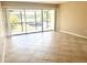 Bright living room with tiled floor, sliding glass doors to balcony, and neutral walls at 2938 Clark Rd # 203, Sarasota, FL 34231