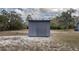 A gray standalone storage shed surrounded by sand and trees on a sunny day at 31860 Taylor Grade Rd, Duette, FL 34219