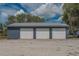 A three car garage has matching siding and roofing and three white garage doors at 31860 Taylor Grade Rd, Duette, FL 34219