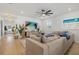 Spacious living room with light wood floors, a modern sectional sofa, and a large screen TV at 3443 74Th Avenue E Cir, Sarasota, FL 34243