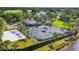 Aerial view of tennis courts, volleyball court and clubhouse with beautiful landscaping and lake views at 3519 Founders Club Dr, Sarasota, FL 34240